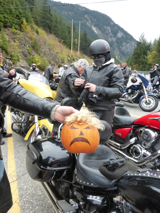 A motorcyclist holing a frowning pumpkin with a shock of unruly yellowish hair. He told me it was "Donald Trumpkin"